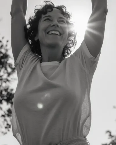 Femme souriante les bras levés vers le ciel, symbolisant l'espoir de retrouver l'amour.